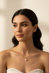 Elegant female model wearing Le Pearl gold and pearl pendant necklace