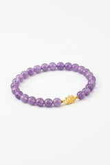 Luxury spiritual bracelet with lavender amethyst beads and gold lotus charm, angle view